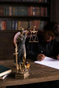 Close-up of Lady Justice figurine on a lawyer's desk with books and documents.